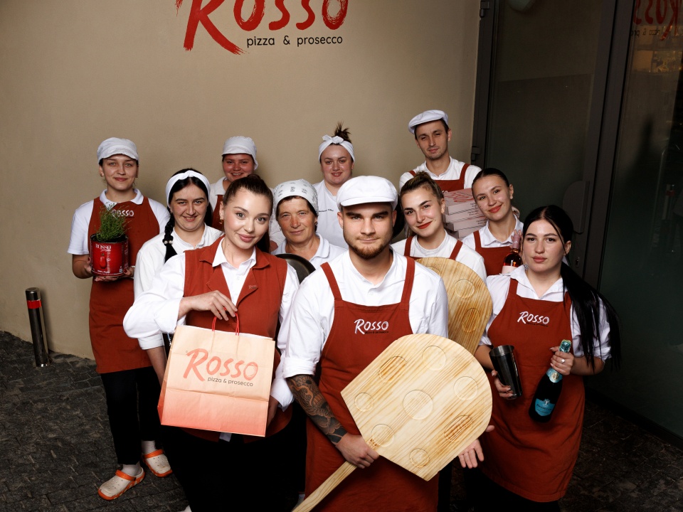 Команда закладу з піцайольськими лопатами біля вивіски Rosso