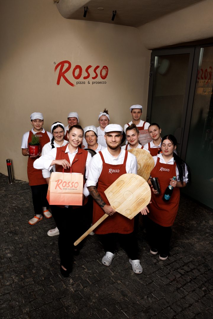 Команда закладу з піцайольськими лопатами біля вивіски Rosso